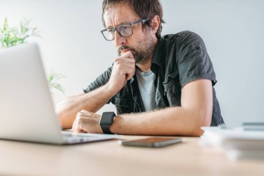 Ev içi ofis içi video konferansı sırasında laptop ekranına bakan serbest yazar, seçici odaklanma