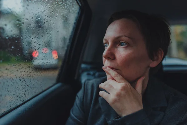 忧心忡忡的女商人在车里等着 在雨中看着窗外 有选择地集中精神 — 图库照片