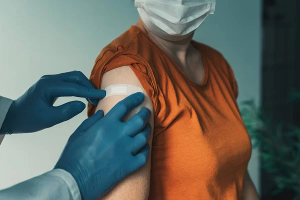 Covid 19ワクチン接種後の女性肩に石膏を適用する医師 予防接種の概念 — ストック写真