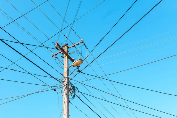青い空に対して乱雑な線を持つ電柱 — ストック写真