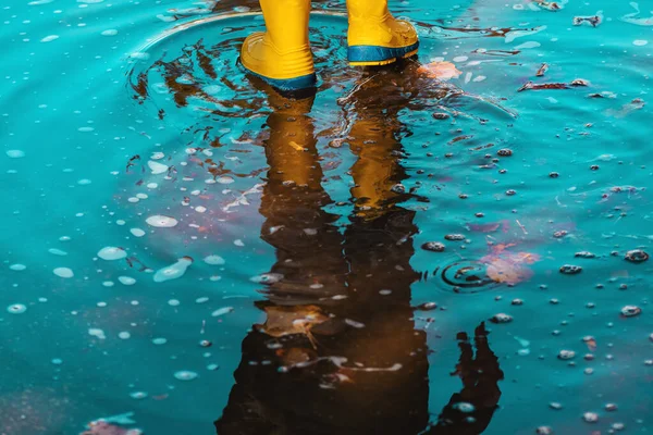秋の午後に濡れた歩道を歩くゴム製のレインブーツを持つ子供 選択的な焦点 — ストック写真