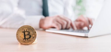 İşadamı bilgisayarının başında bitcoin kripto para ticareti platformu ile ticaret yapıyor, önüne bozuk paralar yığıyor, seçici odaklı panoramik görüntü