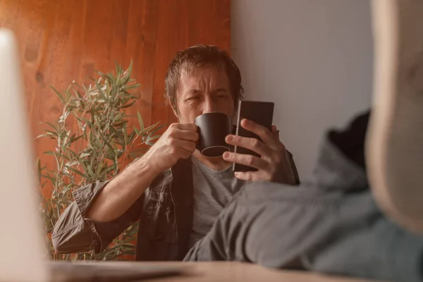 프리랜서가 커피를 마시고 사무실에서 스마트폰을 사용하고 긴장을 선택적으로 — 스톡 사진
