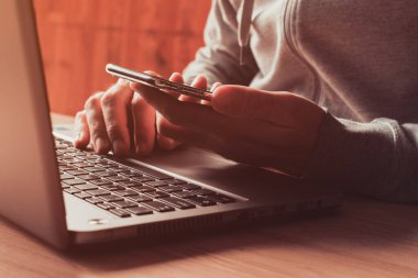 Ofiste akıllı telefon ve laptop kullanan serbest çalışan seçici odaklı yakın plan.