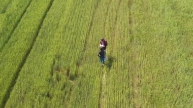 Mortgage loan officer assisting farmer in financial allowance application process, banker and farm worker in wheat field. Aerial view from drone pov