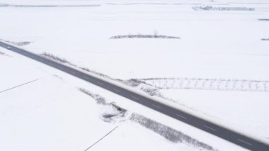 Aerial shot of cars on the snowy road in white winter landscape, drone footage from above