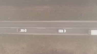 Aerial view of traffic, cars and truck on the road through countryside in foggy morning, top down drone footage
