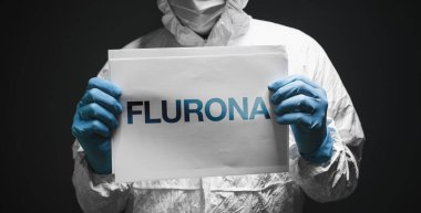 Flurona, infection with both seasonal flu and Covid 19 coronavirus, conceptual image with epidemiologist holding white paper with text, selective focus