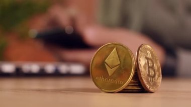 Ethereum and Bitcoin cryptocurrency trader, business person using modern technology electronic to trade with crypto money, stacked coins in the foreground and defocussed businessman in background