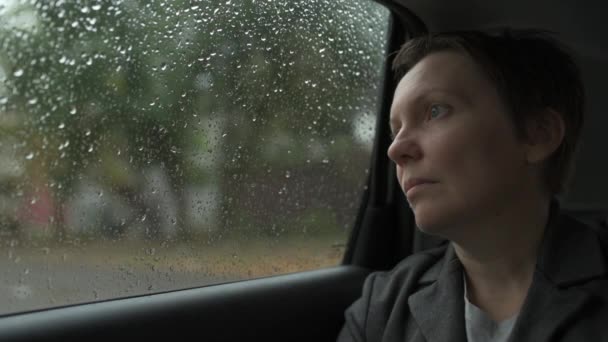 車の中で待っていると雨の中で窓の外を見て心配ビジネス女性 選択的な焦点 — ストック動画