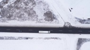 Yarı karavan kamyonunun ve kışın yolda bir sürü arabanın hava görüntüsü. Kış yolundaki trafiğin tepeden aşağı insansız hava aracı görüntüleri.