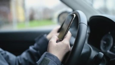 Otoparkta arabanın içinden akıllı telefondan mesaj yazan bir kadın. Seçici bir odak noktası.