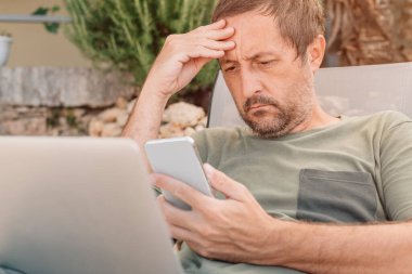 Serbest çalışan ve dijital göçebe yaz tatili boyunca akıllı telefon ve dizüstü bilgisayarda çalışıyor.