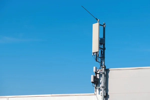 手机信号中继器天线安装在工业大楼顶部 蓝天为复制空间 — 图库照片