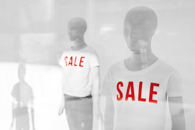 Moda mağazası vitrininde indirimli tişörtlü manken, seçici odaklı