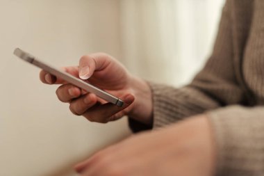 Oturma odasında iletişim kurmak için akıllı telefon kullanan kadın ellerinin kapatılması, seçici odaklanma