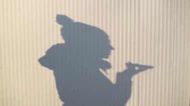 Kışın öğleden sonra cep telefonu kullanan bir kadının gölgesi