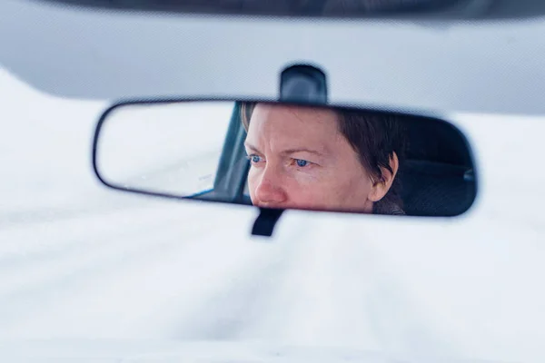 在暴风雪期间 一名女司机在汽车后视镜中 在恶劣的驾驶条件下驾驶时的脸 选择性地聚焦 — 图库照片