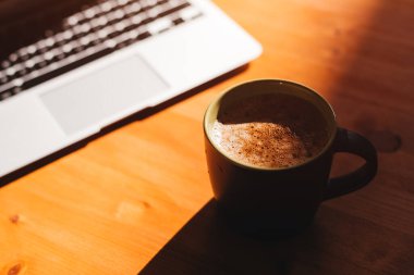 Ofiste kahve molası, dizüstü bilgisayar ve kahve fincanı masada, seçici odaklanma.