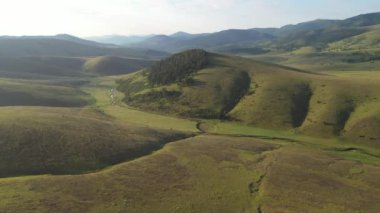 Güneşin doğuşundaki güzel Zlatibor dağ manzarası, İHA pov 'dan hava manzarası. Çimenli tepe yamaçlar ve vadiler yukarıdan.