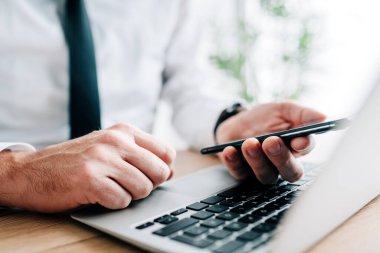 Çalışkan işadamı ofis dizüstü bilgisayarı üzerinde çalışırken kısa mesaj bildirimi okuyor, seçici odaklanma