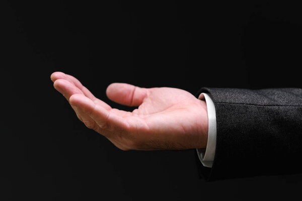 Businessman pleading hand reaching out from the dark, selective focus