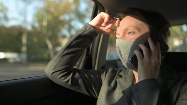 Ernstige Zakenvrouw Met Beschermende Gezichtsmasker Praten Mobiele Telefoon Vanaf Achterbank — Stockvideo