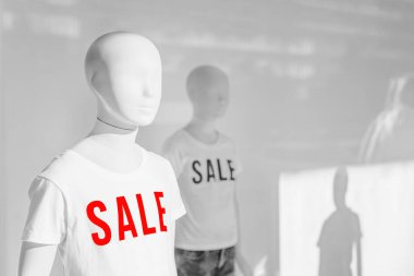 Moda mağazası vitrininde indirimli tişörtlü manken, seçici odaklı