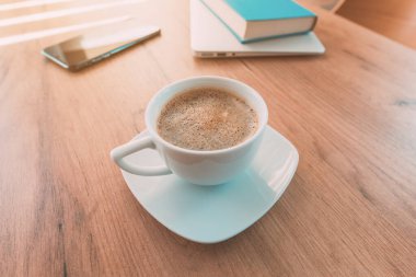 Serbest çalışmak için kafein ve kahve ithalatı. Kahve fincanı, cep telefonu, dizüstü bilgisayar ve ofis masasında bir kitap..