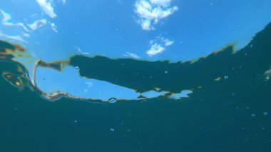 Su altı gökyüzü manzarası ve deniz suyu yüzeyindeki bulutlar soyut arkaplan olarak görülür.