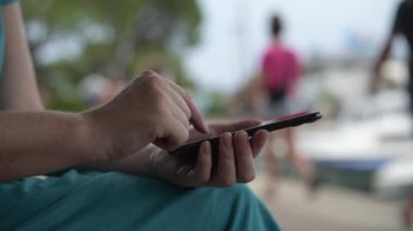 Parkta akıllı telefon kullanan bir kadın, cep telefonuyla kadın ellerini kapatıyor, seçici bir şekilde odaklanıyor.