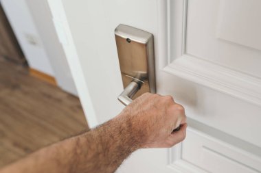 Man opening apartment door, closeup of male hand on handle, selective focus