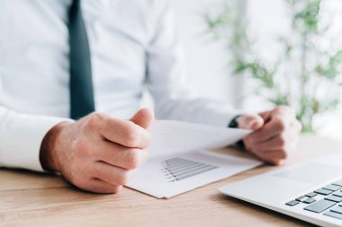 İş adamı iş sonuçlarını analiz ediyor. Ofiste raporlar, seçici odaklanma