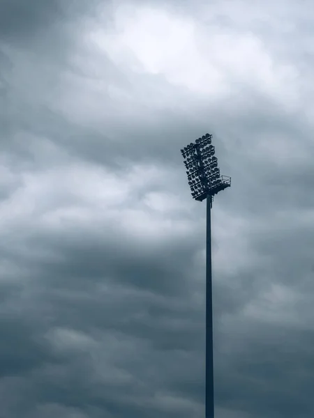 嵐の前の暗い不吉な空に対するスタジアムのライト — ストック写真