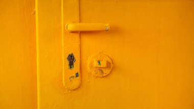 Old yellow door with handle, rough surface as grunge background