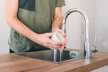 Mutfak lavabosunda kahve fincanı yıkayan adam, seçici odaklanma