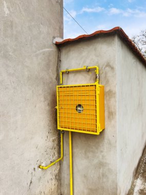 Evin duvarına sarı koruyucu kaplamalı gaz sayacı yerleştirildi.