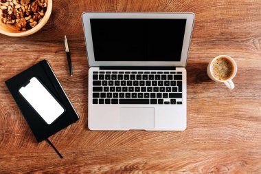 Ev konseptinde çalışmak, laptop bilgisayarı ve masadaki akıllı telefon maketi ekranı ile çalışma alanının üst görünümü