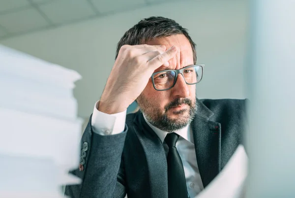 オフィス生活の中で頭痛を引き起こす深刻なビジネス状況 ノートパソコンの画面と思考を見ているビジネスマンを心配し 選択的な焦点 — ストック写真
