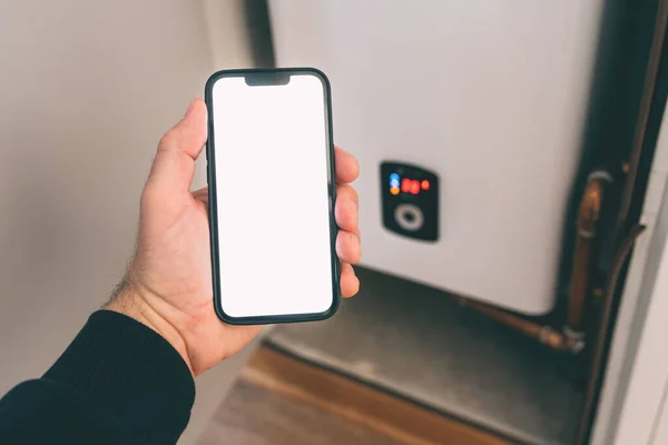 Smart home heating system, man holding smartphone with blank screen for Wi-Fi control app mockup, selective focus