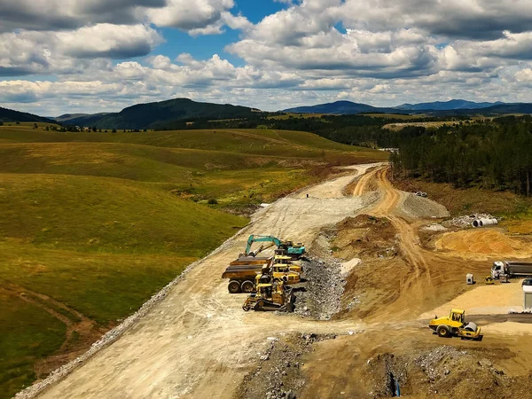 Road construction and heavy industrial machinery at Zlatibor, aerial view from drone pov on sunny summer day