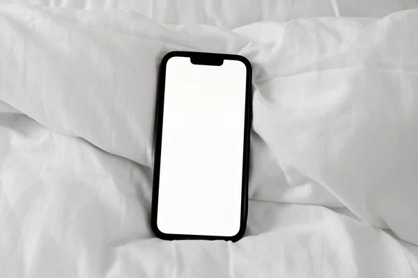 Smartphone mockup screen on white bed sheet, top view flat lay