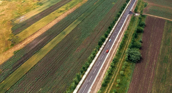 空中拍摄的穿过农村的公路交通 公路上无人驾驶汽车的图像和人行道上行走的行人 — 图库照片