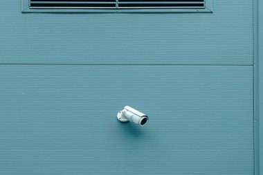 Endüstriyel bina duvarına yerleştirilmiş güvenlik kamerası binanın dışındaki aktiviteleri izlemek için.