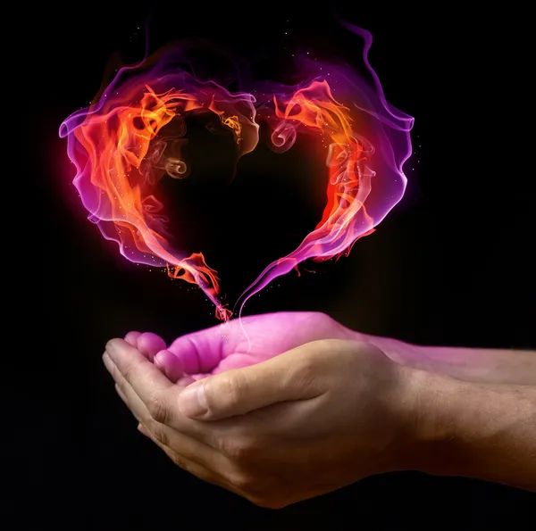 St. Valentin van hart branden op de handen tegen donkere achtergrond — Stockfoto