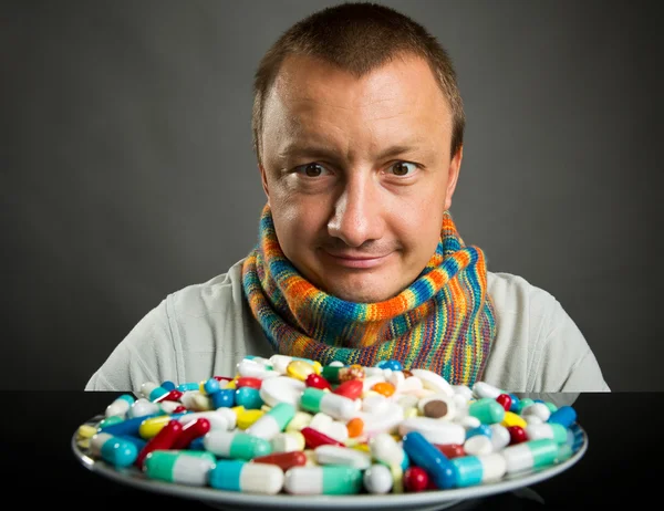 Hombre mirando en el plato lleno de pastillas — Foto de Stock