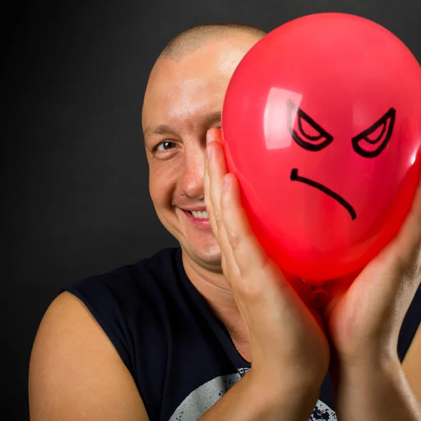 Homem feliz escondido atrás de balão zangado — Fotografia de Stock