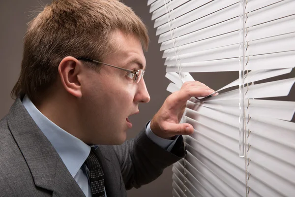 Man en venster jaloezieën — Stockfoto