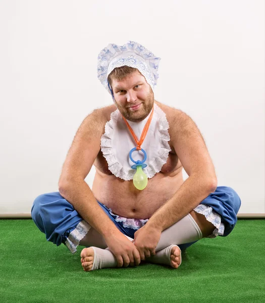 Mann trug als Baby auf Gras sitzend — Stockfoto