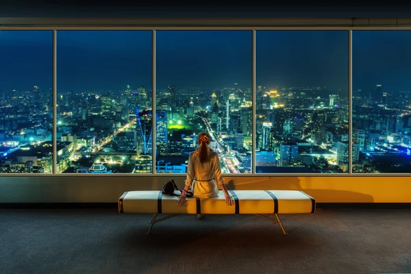 Mujer mira el paisaje urbano nocturno — Foto de Stock